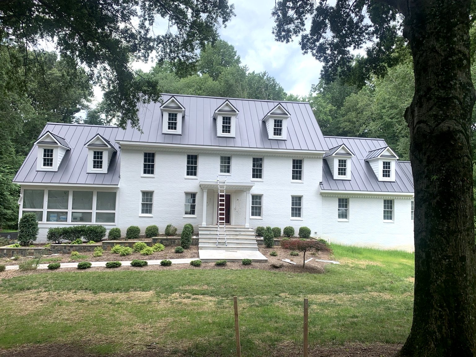 Finished gray standing seam metal roof on white brick home